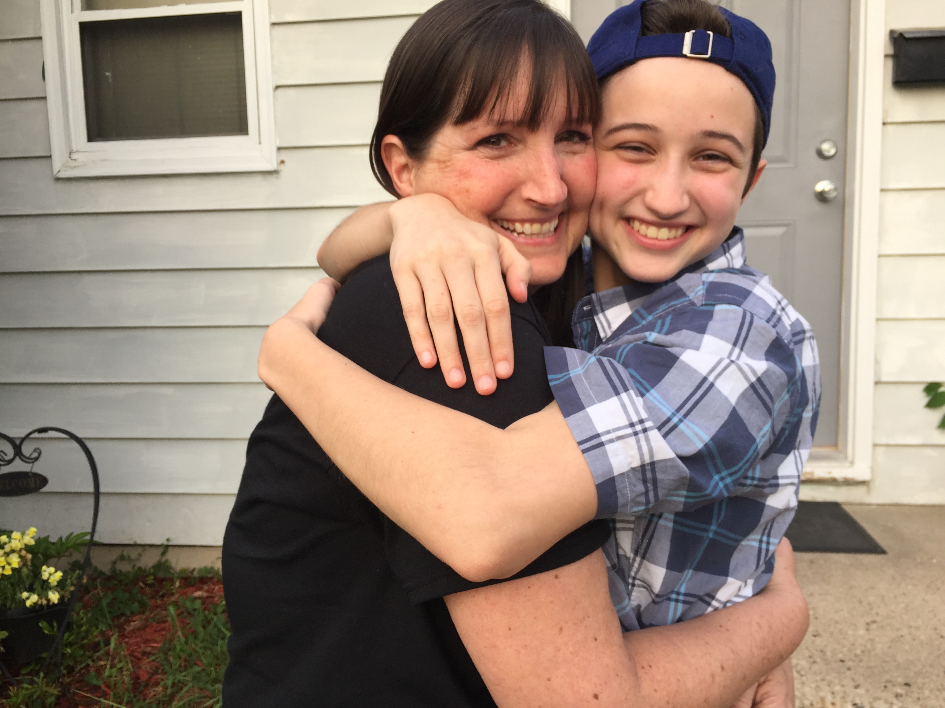 TLC client Ash Whitaker hugs his mom as they smile outside their house