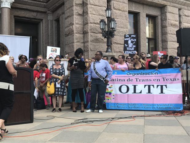 A gathering of people with a banner being held, that says: "Organizacion, Latina de Trans en Texas. OLTT"