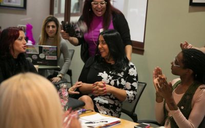 Members of TLC's Positively Trans program gather around a table laughing and applauding