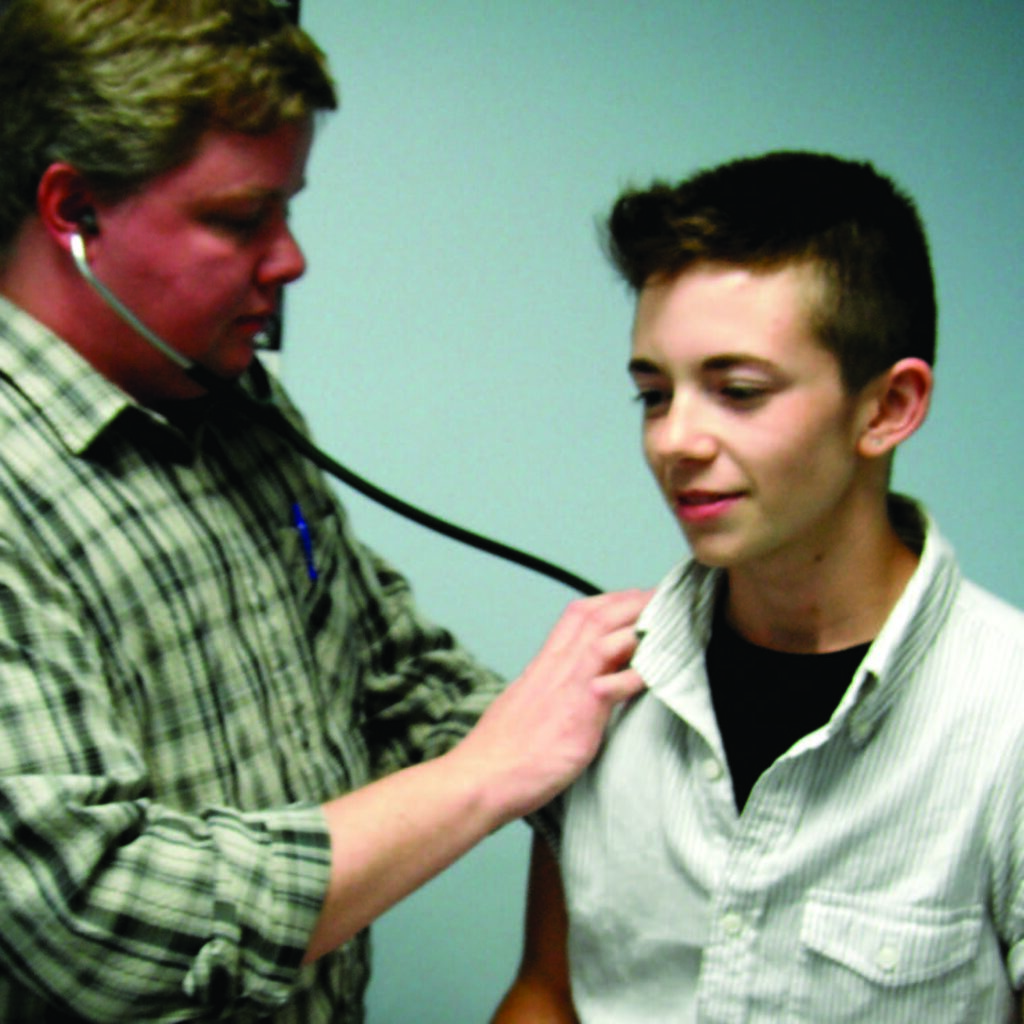 A doctor using a statoscope to preform a checkup on a minor.
