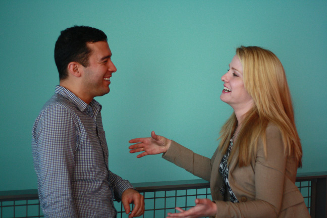 A man and woman laughing while having a casual conversation.