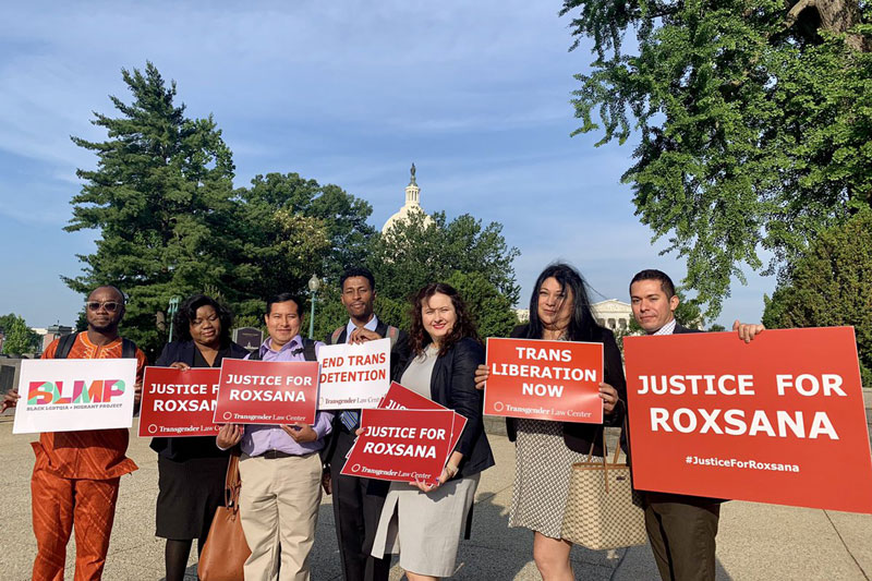 A group of diverse people holding up bright signs that say "Justice for Roxsana"