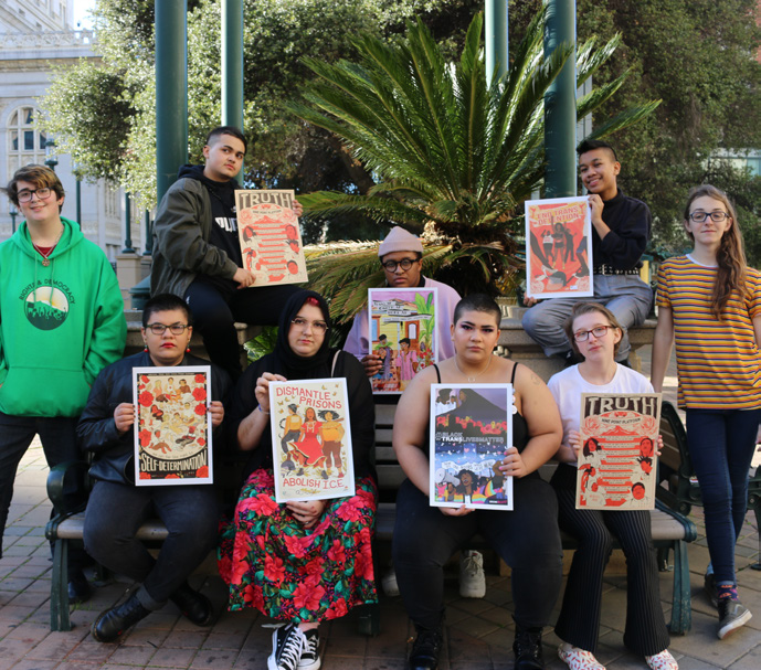 Photo of a group of nine members of the National Trans Youth Council holding posters they created