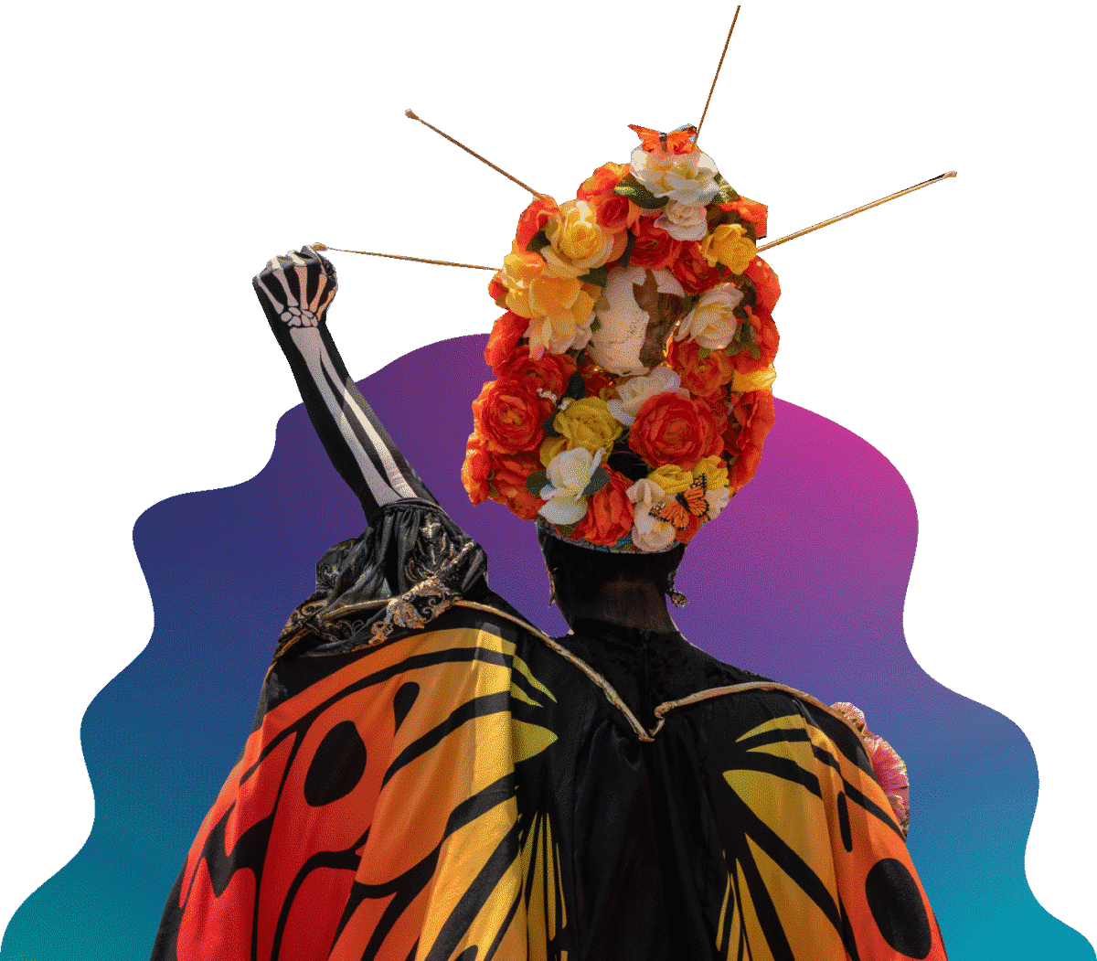 A person with their back turned wearing orange and yellow butterfly wings and a flower headdress raising their fist.